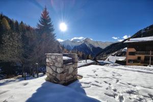 un techo cubierto de nieve de un edificio con el sol en el cielo en - La Casetta di Legno - i colori della natura, en Foppolo