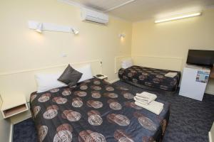 a hotel room with two beds and a flat screen tv at Pioneer Station Motor Inn in Swan Hill
