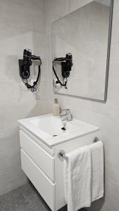 Baño blanco con lavabo y espejo en Imperial Apartamentos Puerto, en Valencia