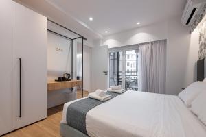 Kriel Suites by LIV Homes في أثينا: غرفة نوم بيضاء مع سرير كبير ونافذة