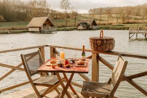 een tafel met twee stoelen en een fles wijn op een steiger bij Aqualodge Hôtel Insolite in Ermeton-sur-Biert