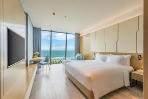 a hotel room with a bed and a view of the ocean at Awaken Da Nang Hotel in Danang