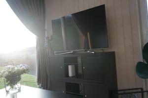 einen Flachbild-TV an einer Wand mit einem Fenster in der Unterkunft Tinyhouse Heimatglück in Bad Berleburg