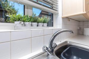 a kitchen with a sink and a window with plants at Lark Rise Apartment- 3BR in Ifield