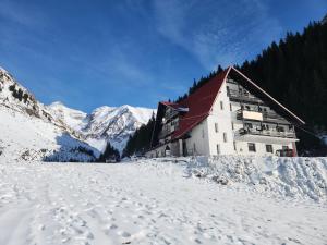 a building in the snow with mountains in the background at Hotel Paraul Capra in Cumpăna