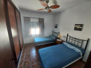 - une chambre avec 2 lits et un ventilateur de plafond dans l'établissement La encina, à Guillena