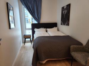 een slaapkamer met een bed, een stoel en een raam bij Fefe's Luxury Rooms in Ask Gjerdrum/Oslo in Gjerdrum