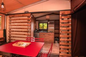 cocina y comedor con mesa roja en Camping Onlycamp de Wasselonne, en Wasselonne