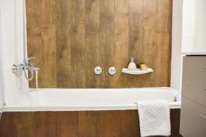 a bathroom with a bath tub with a wooden wall at La Neu Studio neuf pour 4 pax en centre ville in Pas de la Casa