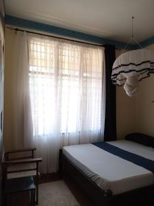 - une chambre avec un lit et une fenêtre avec des rideaux dans l'établissement Marieella homes, à Ukunda