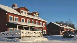 a large red building with a white fence in the snow at Ottsjö Wärdshus in Undersåker