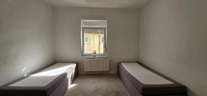 a white room with two beds and a window at Timeless: 4 Zimmer Apartment OG Ludwigsburg in Ludwigsburg