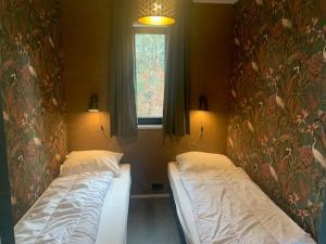 two beds sitting in a room with a window at Wellnesslodge Scholekster met jacuzzi en uitzicht in Dalerveen