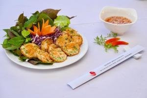 un piatto di cibo con insalata e una ciotola di salsa di Sammy Hotel a Vung Tau