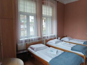 two beds in a room with two windows at Willa Pałacyk in Świeradów-Zdrój