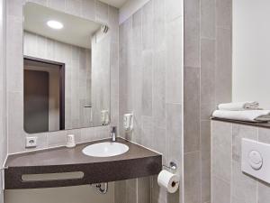 een badkamer met een wastafel en een spiegel bij B&B Hotel Köln-West in Keulen