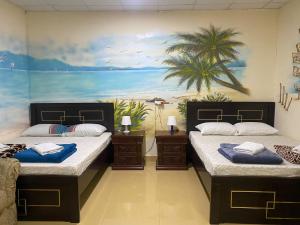 two beds in a room with a painting on the wall at Backpackers Place - Central Bus Terminal in Abu Dhabi