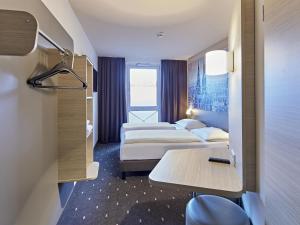 a hotel room with two beds and a table at B&B Hotel Köln-West in Cologne