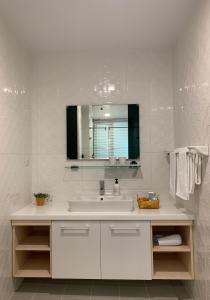 uma casa de banho branca com um lavatório e um espelho em 珍遇珍寓電梯民宿 June June House em Tainan