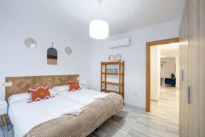 Schlafzimmer mit einem Bett mit weißer Bettwäsche und orangefarbenen Kissen in der Unterkunft Grace Apartments - 3 bedroom City Centre in Granada