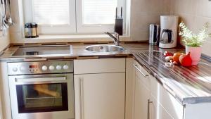 a kitchen with a sink and a stove at Feriendorf Südstrand Haus 21 in Pelzerhaken +14 photos