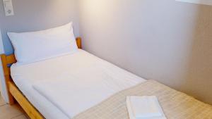 a small bed with white sheets and a pillow at Feriendorf Südstrand Haus 21 in Pelzerhaken