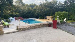 a swimming pool in a yard with a stone wall at La studette provençale in Jouques
