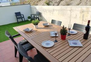 - une table en bois avec des chaises et une bouteille de vin dans l'établissement Ático con terraza y vistas a la montaña en Arenys by Alterhome, à Arenys de Munt