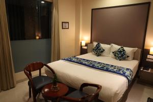 Hotel Pinaka Inn في لاكناو: غرفه فندقيه بسرير وكرسيين