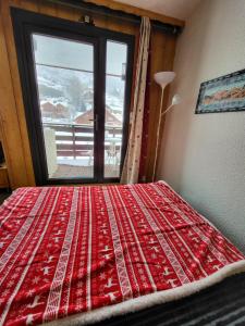 a red bed in a room with a window at Les Mélèzes in Saint-Chaffrey