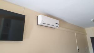 un aire acondicionado montado en la pared en una pared junto a una TV en Manzini, Park Vills Apartment, No 103, en Manzini