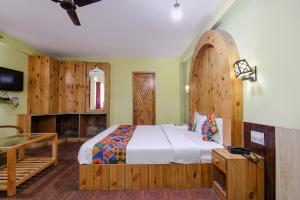 a bedroom with a large bed with a wooden headboard at FabHotel River Bank in Vashisht