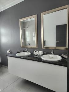 a bathroom with two sinks and two mirrors at La Chambre Manor House in Nelspruit
