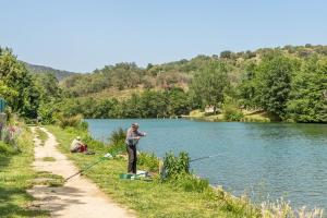 un hombre parado al lado de un río pescando en Camping les Rives du Lac de Vinça, en Vinça