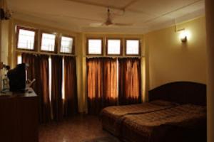 a bedroom with a bed and windows with curtains at Prashaanti Cottage Bhalukpong in Bhalukpung