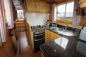 a small kitchen with a sink and a stove at Beautiful New Moon Narrowboat in Cambridge