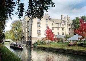 a boat in a river in front of a building at Beautiful Narrowboat Glyndwr in Cambridge