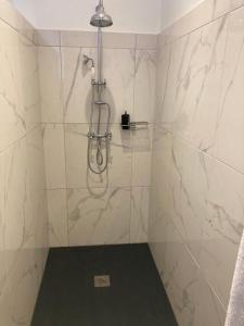 a bathroom with a shower with white marble walls at The Kiosk in Malmedy