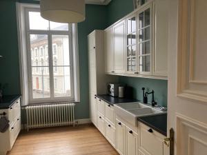 a kitchen with white cabinets and a window and a sink at The Kiosk in Malmedy