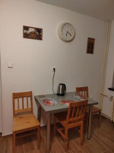 a dining room table with two chairs and a clock on the wall at Mária in Košice