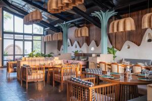 a restaurant with wooden tables and chairs and windows at Kamah, Goa in Anjuna