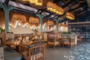a restaurant with wooden tables and chairs and chandeliers at Moyrah By Greenpark in Anjuna