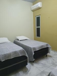 1 dormitorio con 2 camas y ventana en Diária em Família, en Natal