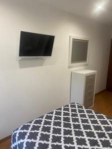 a bedroom with a bed and a flat screen tv on a wall at SANTA MARTA PLAYA BAIONA in Baiona