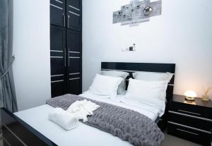 a bedroom with a bed with a black headboard and white pillows at Appart ELRESIDANCIEL Palmiers 2 in Douala