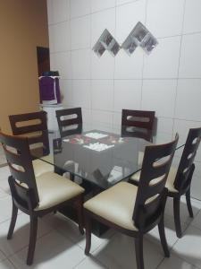 una mesa de comedor con sillas y una mesa de cristal con en Diária em Família, en Natal