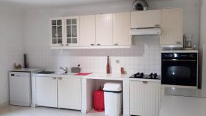 une cuisine avec des armoires blanches et une poubelle rouge dans l'établissement Entre mer et montagne, à La Roque-dʼAnthéron