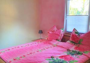 a pink bed with pink sheets and a window at Kölp - Will, Grit und Martin in Kolpinsee