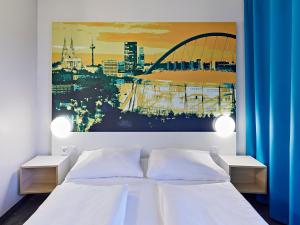 ein Schlafzimmer mit einem weißen Bett und einem Gemälde an der Wand in der Unterkunft B&B Hotel Köln-Messe in Köln