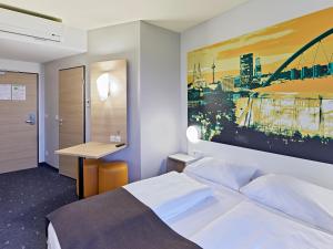ein Schlafzimmer mit einem Bett und einem Schreibtisch. in der Unterkunft B&B Hotel Köln-Messe in Köln